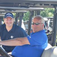 two football alumni in a golf cart